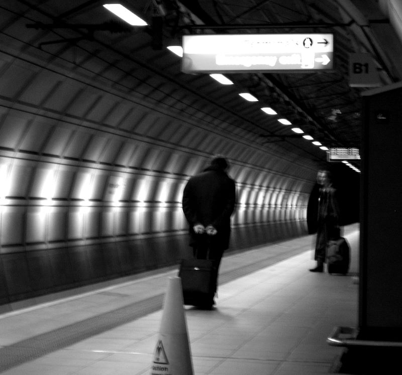 There yet?: Weary travellers waiting for a terminal train in Heathrow airport, UK.